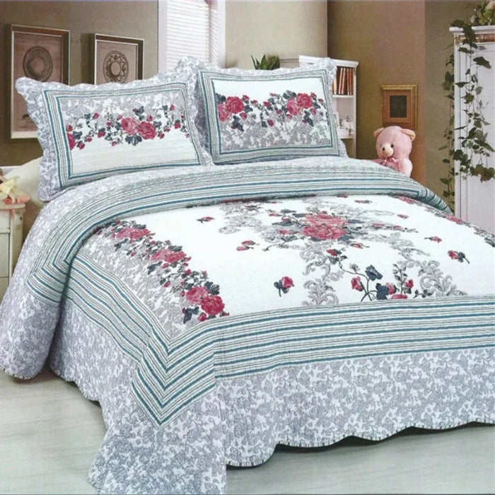 Floral patterned bedspread on a bed in a bedroom setting with a teddy bear.
